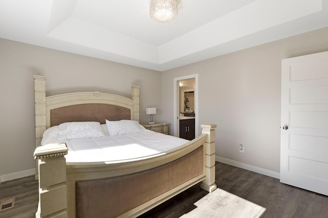 bedroom featuring a notable chandelier, a raised ceiling, dark wood finished floors, and baseboards