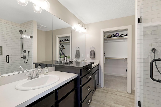 bathroom with a spacious closet, a shower stall, vanity, and wood finished floors