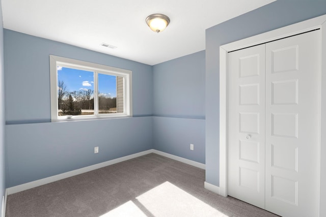 unfurnished bedroom with a closet, carpet flooring, visible vents, and baseboards