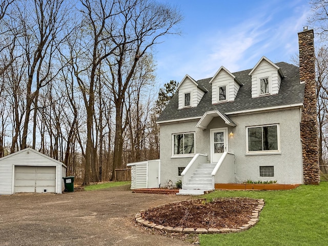 new england style home featuring a garage and an outdoor structure