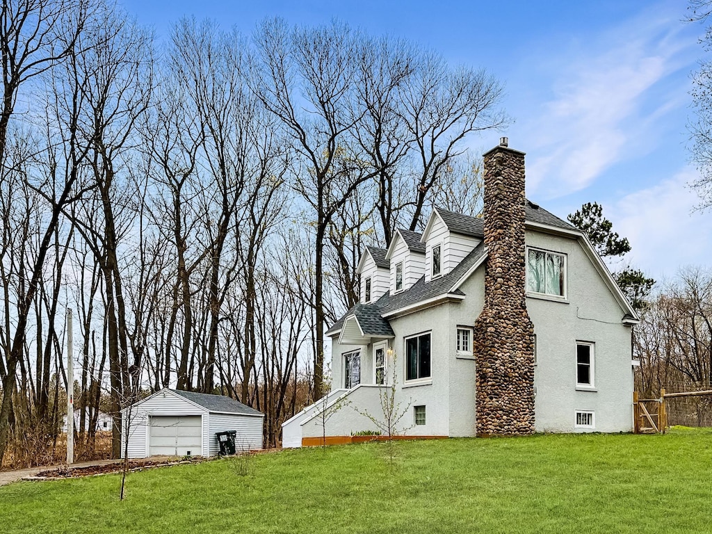 rear view of property featuring a yard, an outbuilding, and a garage