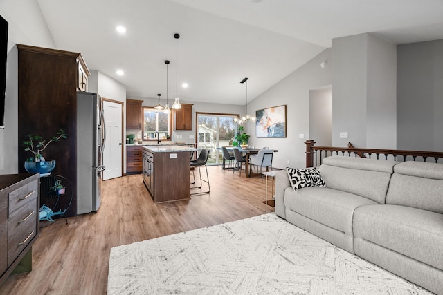 living room featuring light hardwood / wood-style flooring, a chandelier, lofted ceiling, and sink