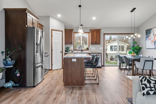 kitchen featuring pendant lighting, a breakfast bar area, light hardwood / wood-style flooring, a kitchen island, and stainless steel appliances