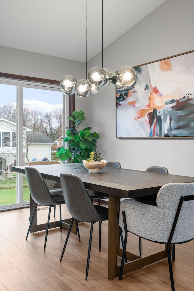 dining room featuring light wood-style flooring and vaulted ceiling