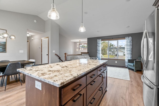 kitchen with a notable chandelier, decorative light fixtures, freestanding refrigerator, light wood finished floors, and vaulted ceiling