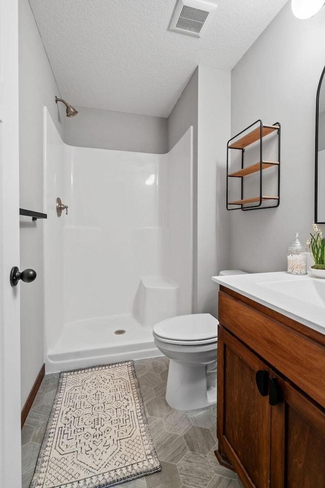 full bath featuring visible vents, toilet, a textured ceiling, walk in shower, and vanity