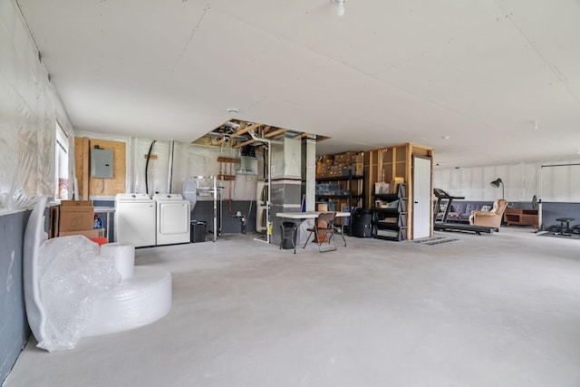 garage featuring electric panel, heating unit, and independent washer and dryer