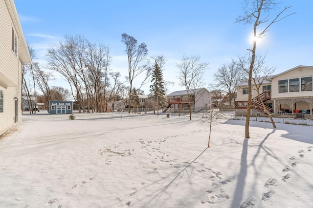 snowy yard with stairway, a residential view, an outbuilding, and a shed