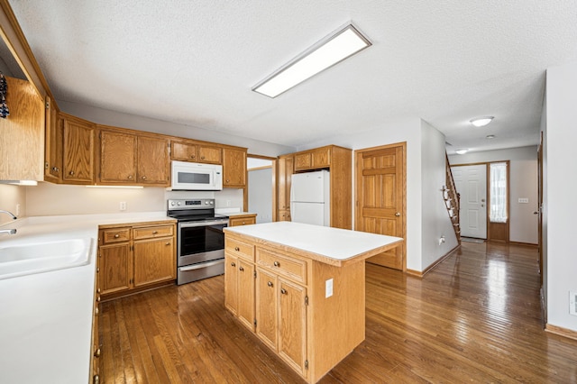 kitchen with dark hardwood / wood-style flooring, white appliances, a textured ceiling, sink, and a kitchen island