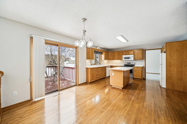 kitchen featuring white appliances, decorative light fixtures, hardwood / wood-style flooring, a chandelier, and a center island