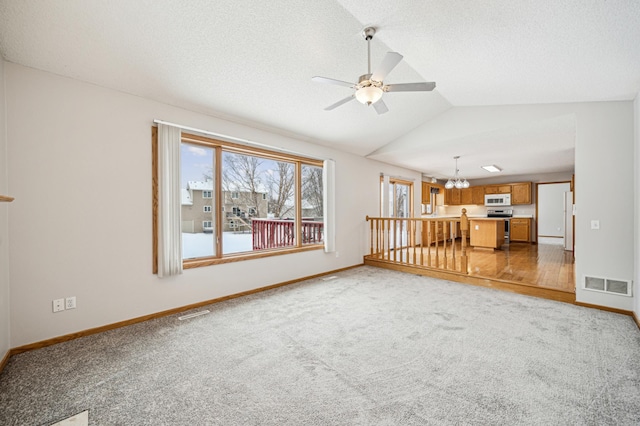 unfurnished living room with carpet, ceiling fan with notable chandelier, and lofted ceiling