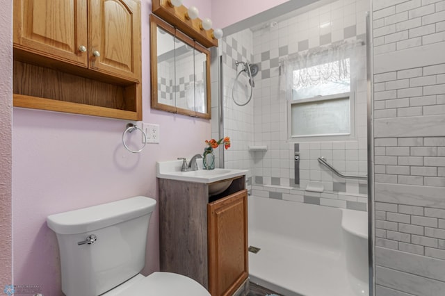 bathroom featuring tiled shower, vanity, and toilet