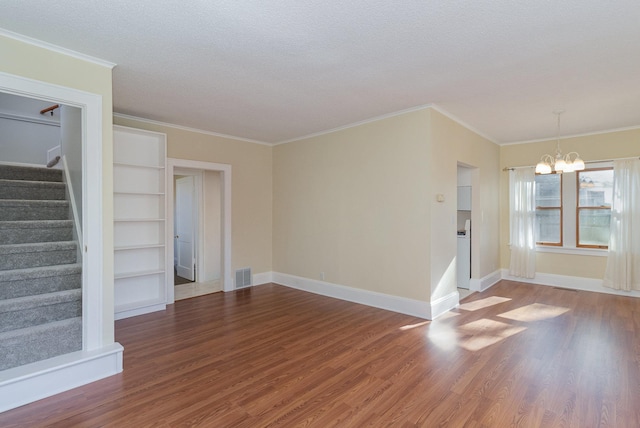 unfurnished living room with hardwood / wood-style flooring, a notable chandelier, ornamental molding, and a textured ceiling