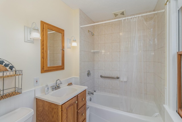 full bathroom featuring a textured ceiling, vanity, tiled shower / bath combo, and toilet