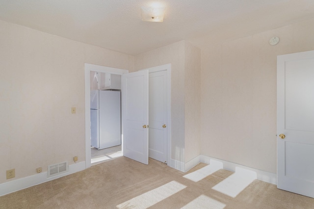 spare room featuring a textured ceiling and light carpet