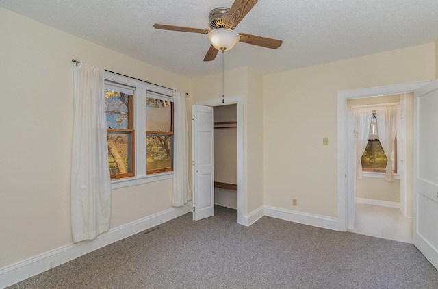 unfurnished bedroom with carpet, ceiling fan, a textured ceiling, and a closet