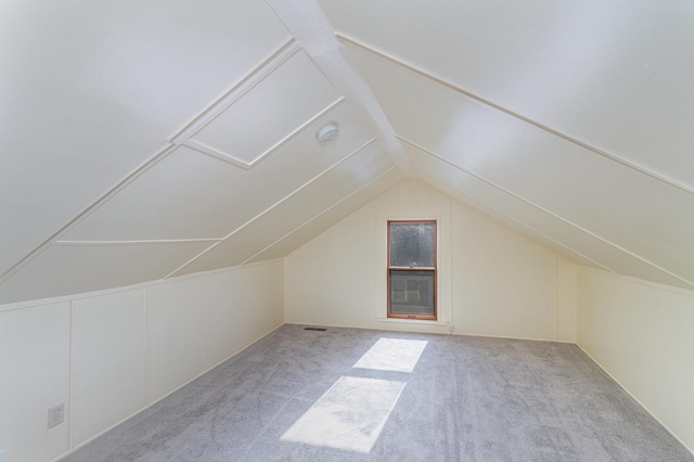 additional living space featuring light colored carpet and vaulted ceiling