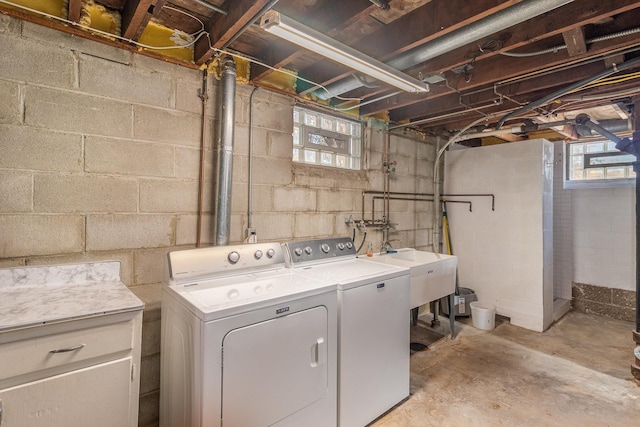 washroom featuring a healthy amount of sunlight, washing machine and dryer, and sink