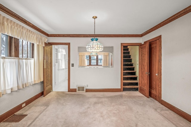 spare room featuring a chandelier, carpet floors, and crown molding