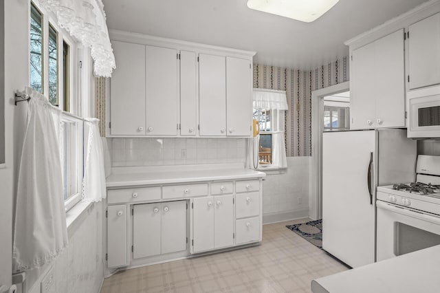 kitchen featuring white appliances and white cabinetry