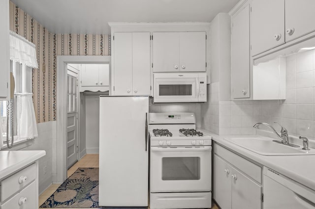 kitchen featuring white appliances, sink, light wood-type flooring, plenty of natural light, and white cabinetry