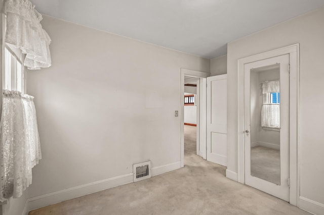 unfurnished bedroom featuring multiple windows and light carpet