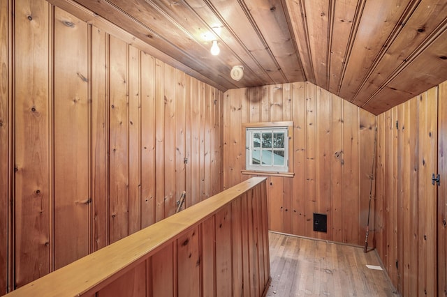 corridor featuring wood-type flooring, vaulted ceiling, wooden ceiling, and wood walls