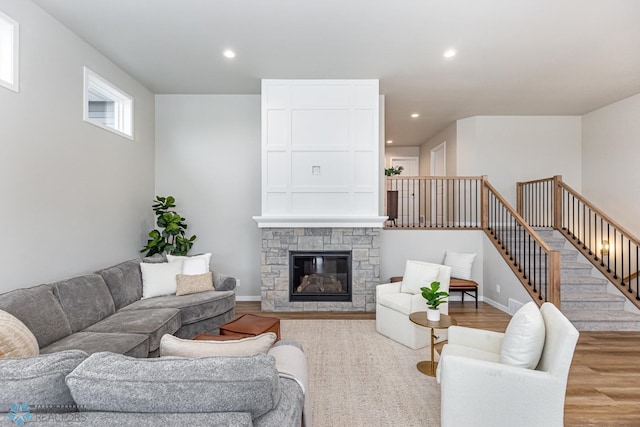 living room with wood-type flooring and a stone fireplace