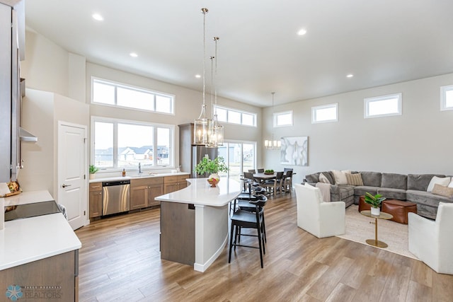 kitchen featuring a breakfast bar, decorative light fixtures, light hardwood / wood-style flooring, dishwasher, and a kitchen island