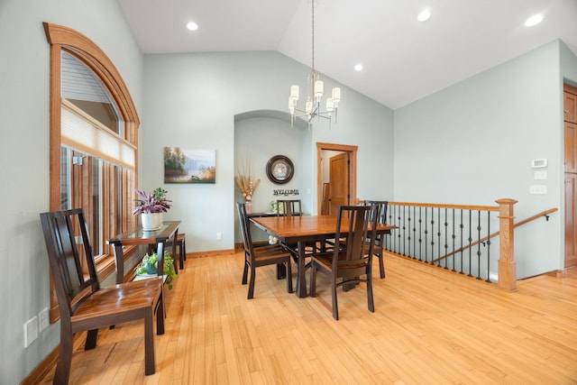 dining space with high vaulted ceiling, a notable chandelier, and light wood-type flooring