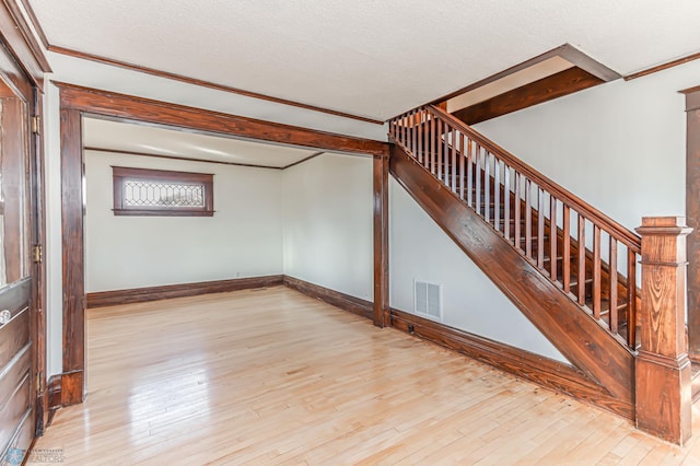 interior space with hardwood / wood-style floors, ornamental molding, and a textured ceiling