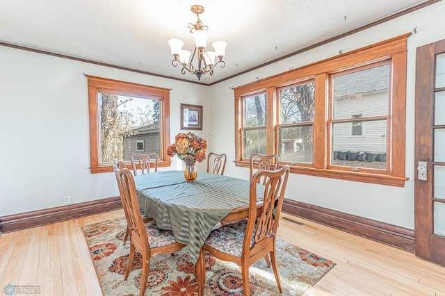 dining space featuring ornamental molding, light hardwood / wood-style floors, and a notable chandelier