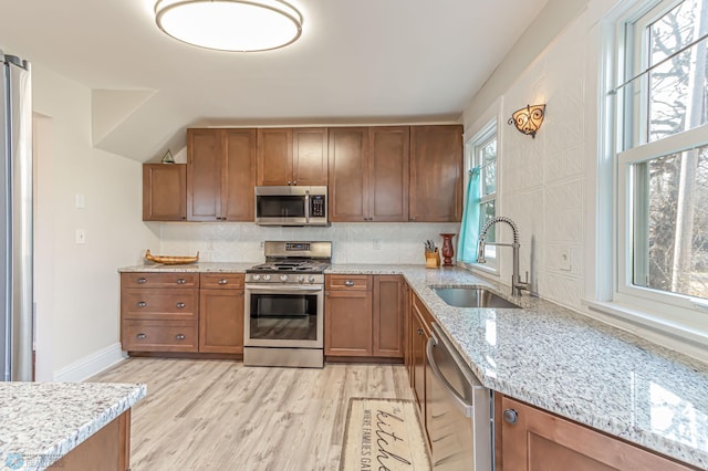 kitchen featuring light stone countertops, stainless steel appliances, light hardwood / wood-style floors, and sink