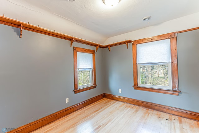 spare room with light hardwood / wood-style floors and vaulted ceiling