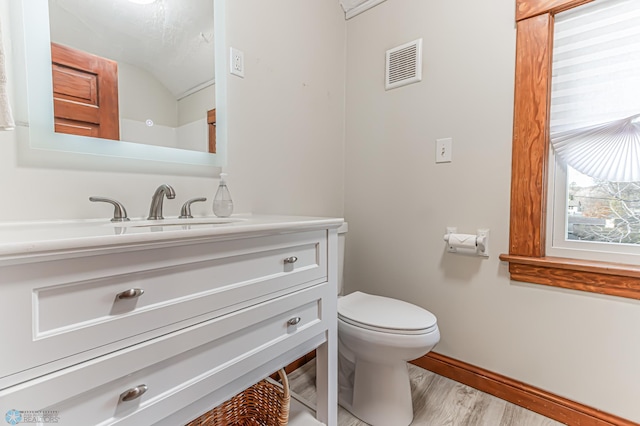 bathroom featuring hardwood / wood-style floors, vanity, toilet, and vaulted ceiling