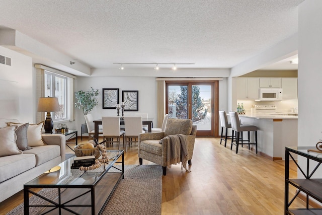 living room with a textured ceiling and light hardwood / wood-style flooring