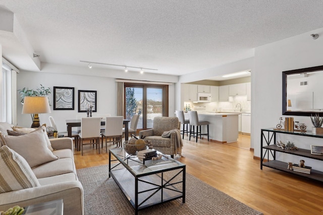 living room with light hardwood / wood-style flooring, rail lighting, and a textured ceiling