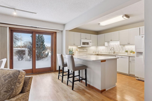 kitchen featuring a textured ceiling, white cabinetry, white appliances, and light wood-type flooring