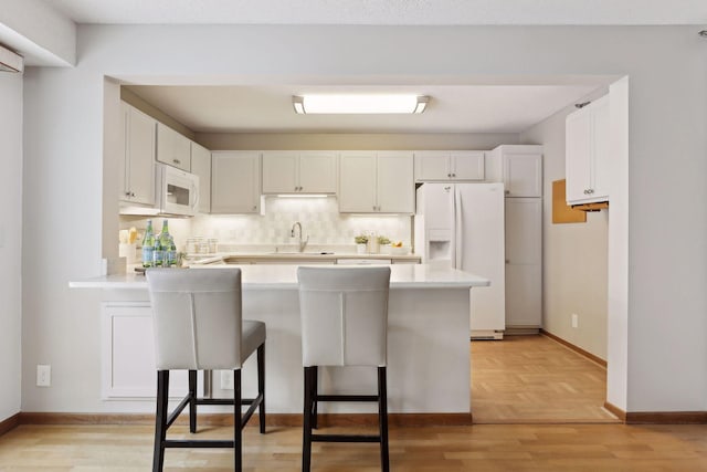 kitchen with white cabinets, white appliances, kitchen peninsula, and a breakfast bar area