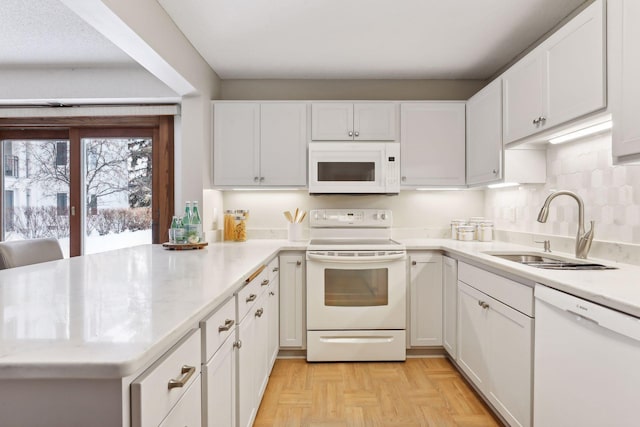 kitchen with white cabinetry, sink, kitchen peninsula, light parquet floors, and white appliances