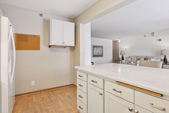 kitchen with white cabinetry, light stone counters, white fridge with ice dispenser, and light parquet floors