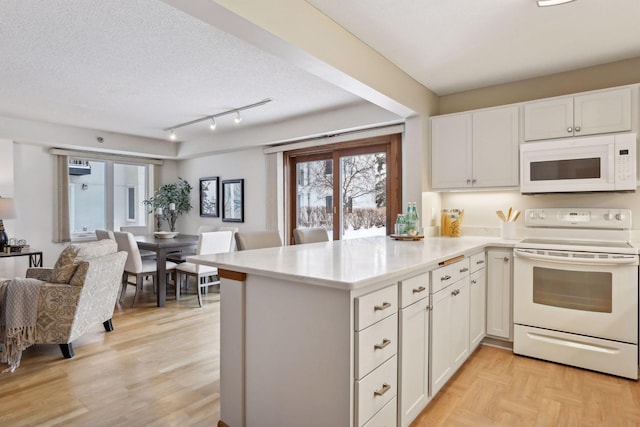 kitchen featuring white cabinets, white appliances, kitchen peninsula, and a textured ceiling