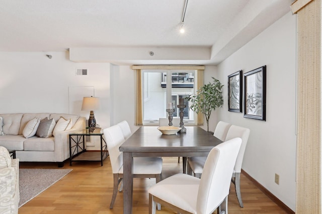 dining room with light wood-type flooring and track lighting