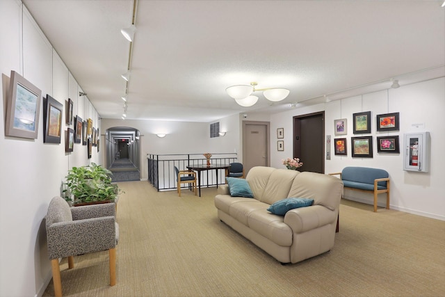 living room featuring a textured ceiling, track lighting, elevator, and light colored carpet