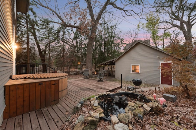 deck at dusk featuring a jacuzzi