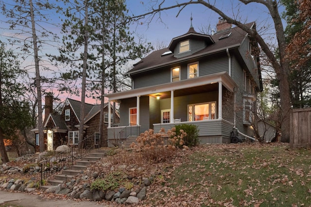 view of front of home featuring fence, covered porch, and a chimney