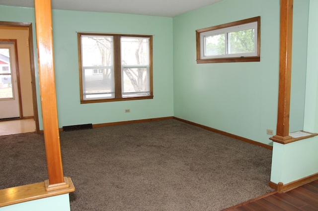 spare room featuring a healthy amount of sunlight and dark colored carpet