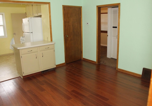 interior space featuring white refrigerator, dark hardwood / wood-style flooring, and kitchen peninsula