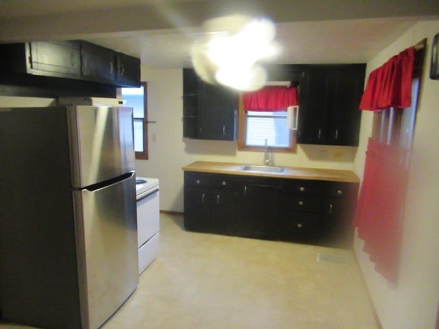 kitchen featuring white range with electric stovetop, stainless steel fridge, and sink