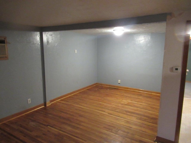 basement with wood-type flooring and a wall mounted AC